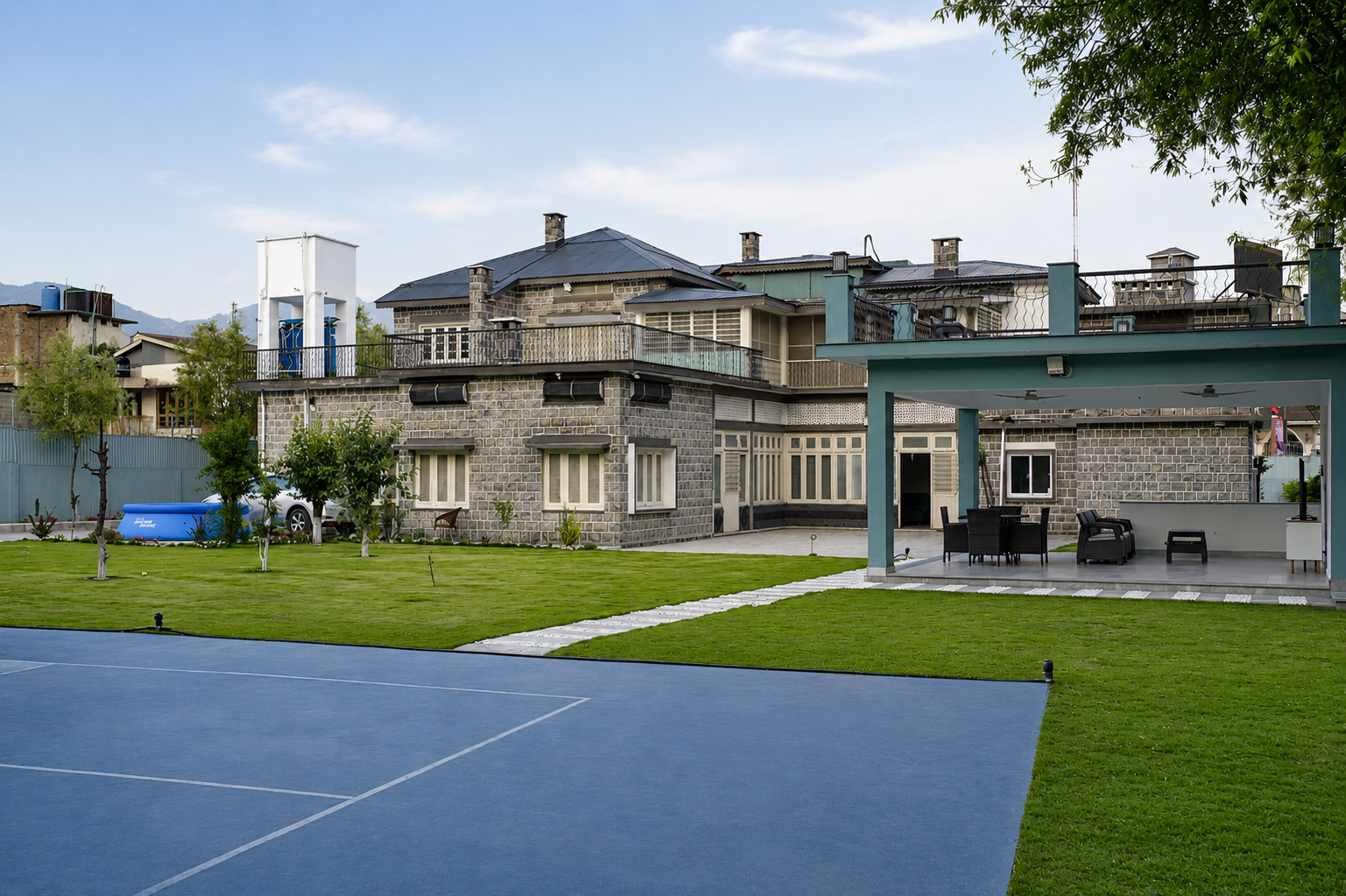 Wide shot of estate grounds: pickleball court, covered pavilion, and mansion