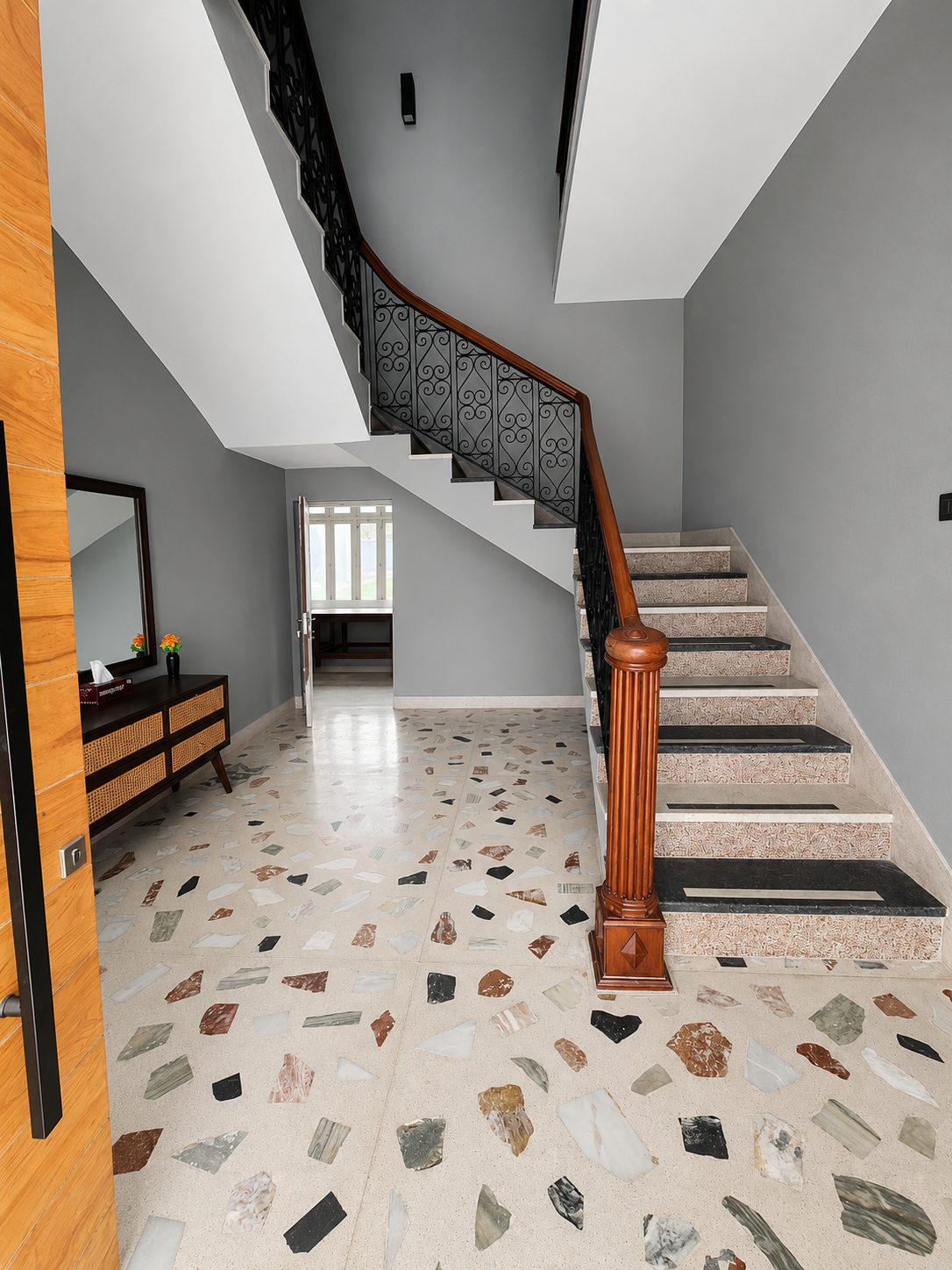 Grand curved staircase with wrought iron railing and terrazzo entry
