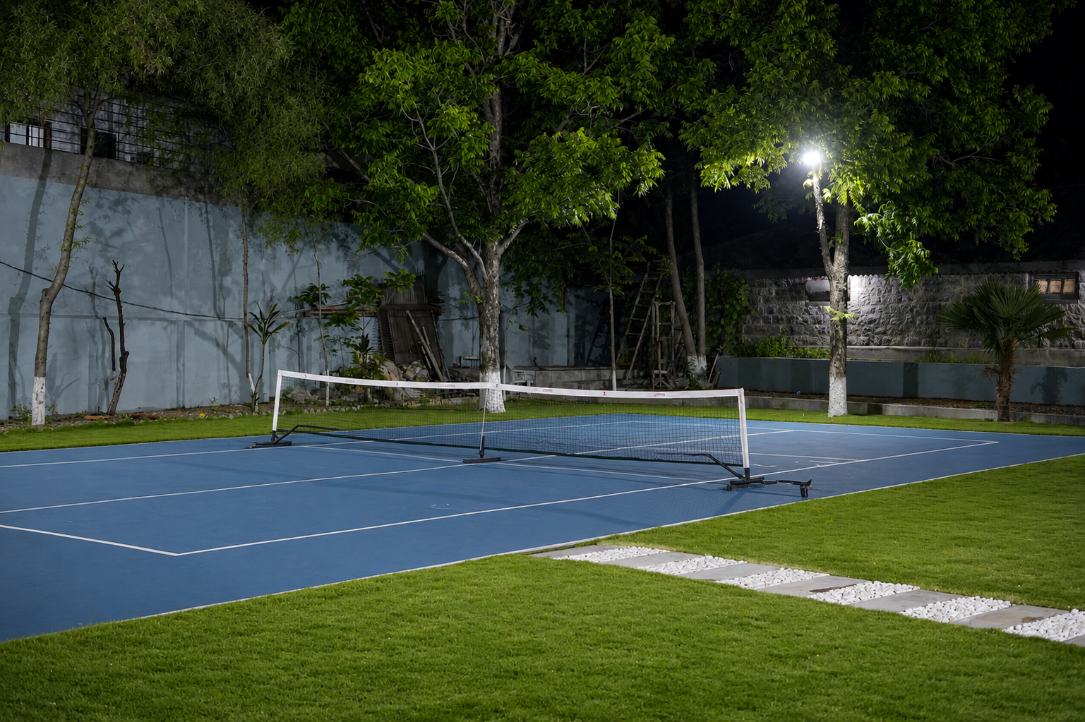 Private floodlit blue pickleball court at night